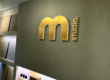 messing logo geborsteld met opaal acrylaat achterzijde gemonteerd op wand.