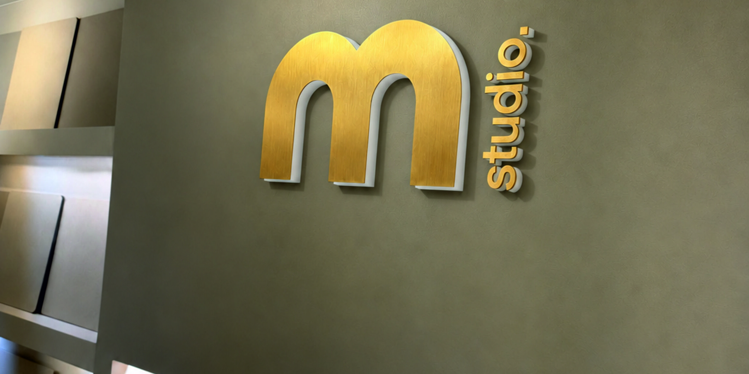 messing logo m studio messing logo geborsteld met opaal acrylaat achterzijde gemonteerd op wand.